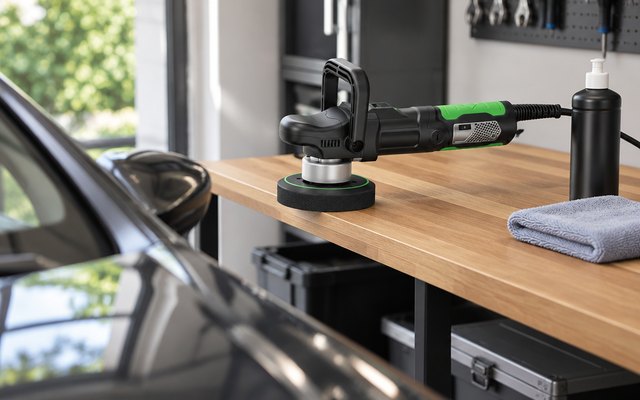 Ginour dual action polisher, on a shelf in a tidy home garage beside a bottle of polish and a microfibre cloth, a car's glossy wing in soft focus
