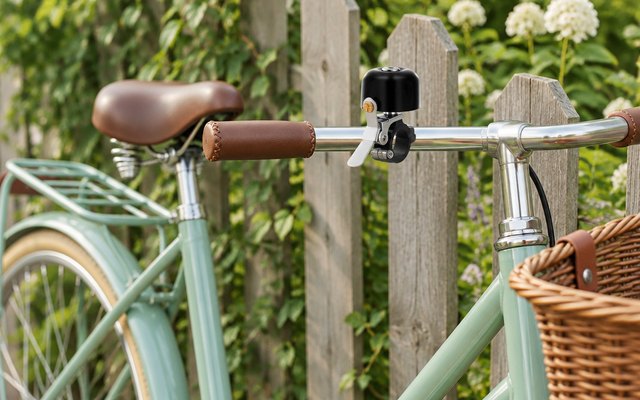 Greallthy metal bike bell, on a step-through bike by a garden fence