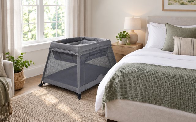Venture Airpod 3 travel cot, beside a bed in a guest bedroom