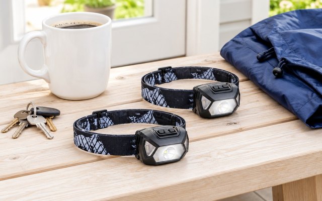Two Lepro rechargeable headlamps on a wooden bench by a sunny back door, beside a coffee mug, keys and a rain jacket