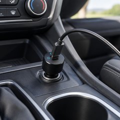 Anker PowerDrive III Duo car charger, plugged into the 12-volt socket in the center console of an SUV, a USB-C cable running from it