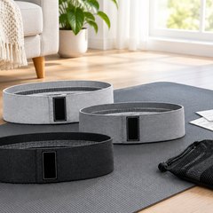 Renoj Fabric Resistance Bands, Set of 3, resistance bands laid on a yoga mat on a light wood floor in a bright living room
