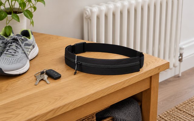 Eono running belt, laid on a hallway bench beside running shoes and keys, a radiator behind