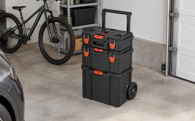 BLACK+DECKER stackable storage system, on the concrete floor of a tidy two-car garage beside a parked bicycle