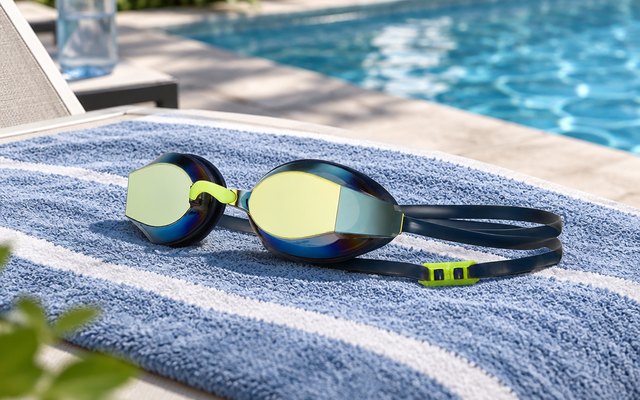 TYR Black Ops 140 EV Racing Swim Goggles, on a towel on a pool lounger