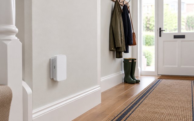 TP-Link RE330 Wi-Fi extender, plugged into a wall socket low down in a bright hallway