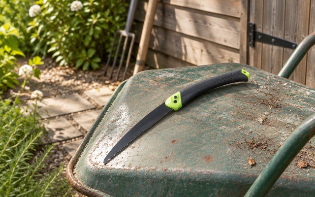WORKPRO folding pruning saw, lying on an upturned wheelbarrow beside a garden shed