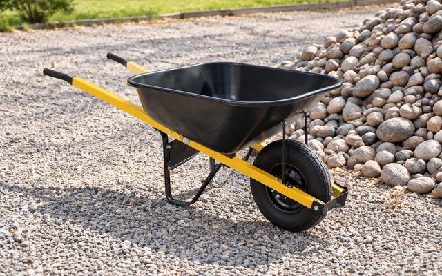 True Temper steel wheelbarrow, on a gravel driveway beside a pile of river rock