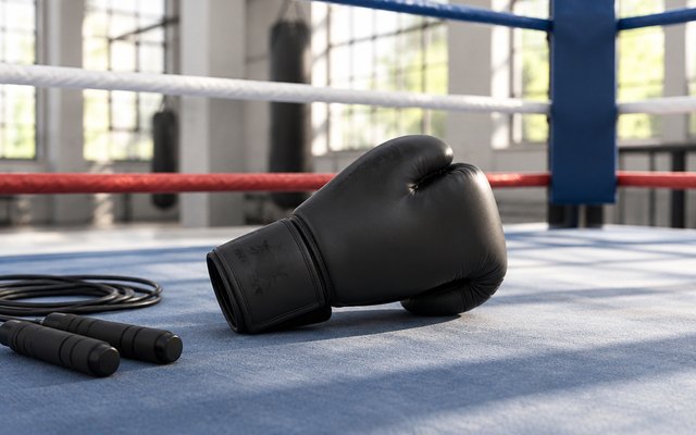 Valchiria training boxing gloves, on the canvas of a boxing ring in a bright gym, beside a jump rope