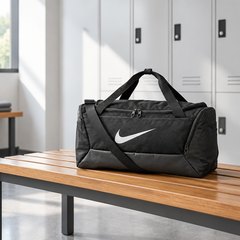 Nike Brasilia duffel bag, on a wooden bench in a bright gym locker room