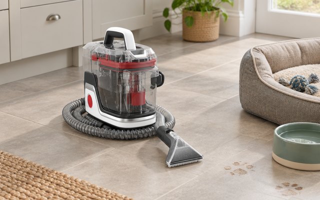 Small portable spot cleaner beside a dog's bed on a kitchen floor