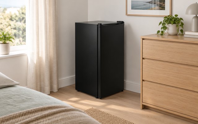 Upstreman mini fridge, in the corner of a calm bedroom beside a dresser