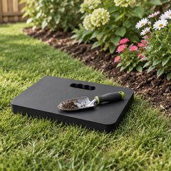 Extra thick kneeling pad, on the grass beside a flower bed in an American backyard, a hand trowel resting on it