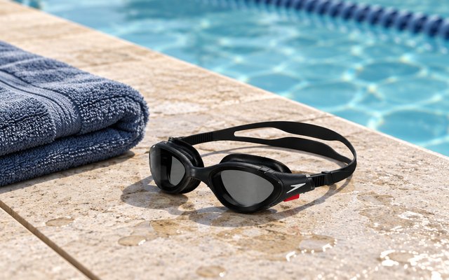 Speedo Biofuse 2.0 goggles, on the deck at the edge of an outdoor swimming pool beside a folded towel