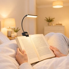 Gritin 19 LED book light clipped to a paperback, read in a bright lamp-lit bedroom