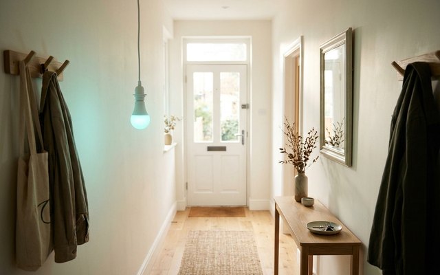 A colour smart bulb in a bare hallway pendant casting a soft teal glow