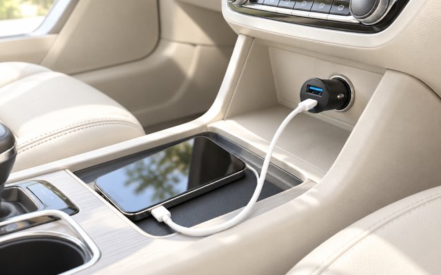 Anker 30W two-port car charger, plugged into the 12V socket of a car with a cream interior, a cable running to a phone in the console tray
