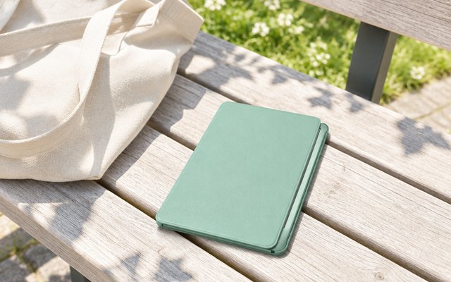MoKo slim e-reader case in mint green on a sunny park bench beside a tote bag