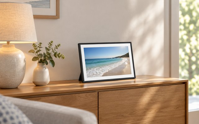 Pastigio Frameo digital picture frame, on a living room sideboard beside a table lamp and a small vase
