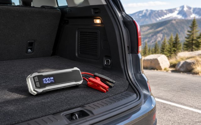 WOLFBOX MegaVolt24 jump starter, on the cargo floor of an SUV with the hatch open in a mountain parking lot