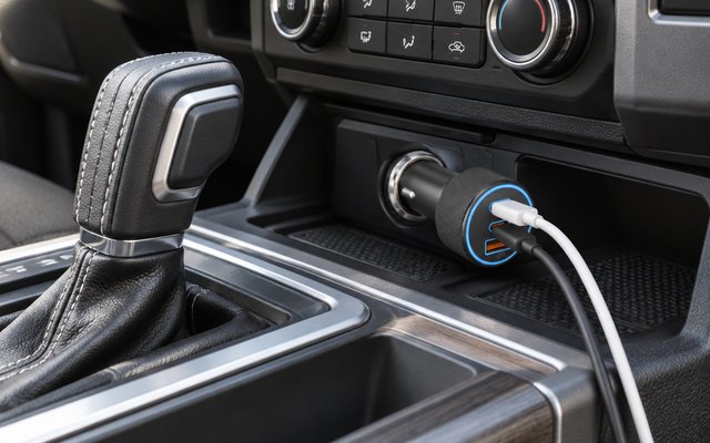 KENHAO 67W car charger, plugged into the 12-volt socket beside the gear shifter of a pickup truck, two charging cables plugged into it