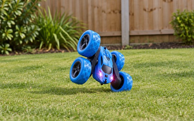 QUNREDA stunt car, flipping over on a freshly mown garden lawn with a wooden panel fence behind