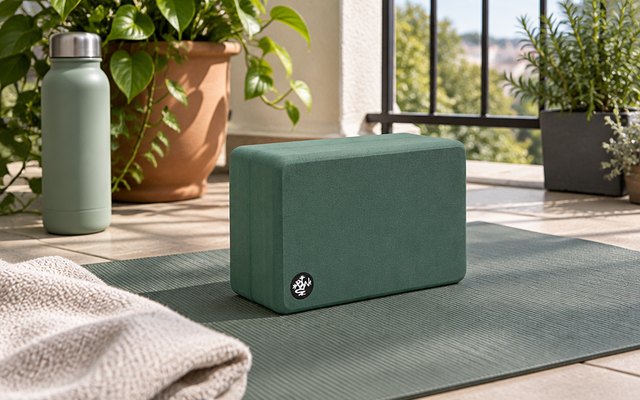Manduka Recycled Foam Yoga Block, on a mat on a balcony with plants