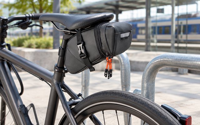 DANUOSIE Expandable Saddle Bag, under the saddle of a commuter bike at a bike rack outside a station