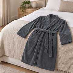 Dark grey plush fleece robe laid out across the end of a bed in a bedroom