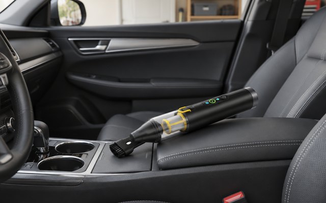 Fanttik Slim V10 APEX car vacuum, on the centre console of a clean car parked in a home garage