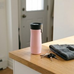 Pale pink travel mug on a sunny oak counter by the front door, beside car keys and a grey toque