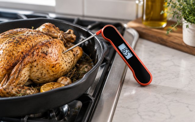 ThermoMonster HT09 thermometer, resting beside a roast chicken in a pan on a kitchen stovetop