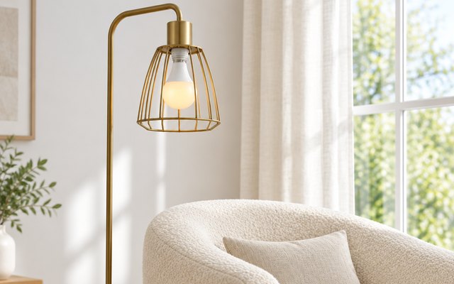 Philips Hue Essential bulb glowing amber in an open cage floor lamp beside an armchair