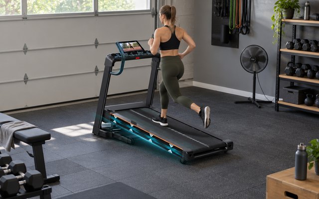 DECORCN folding treadmill, in a converted garage gym with rubber floor tiles and a standing fan